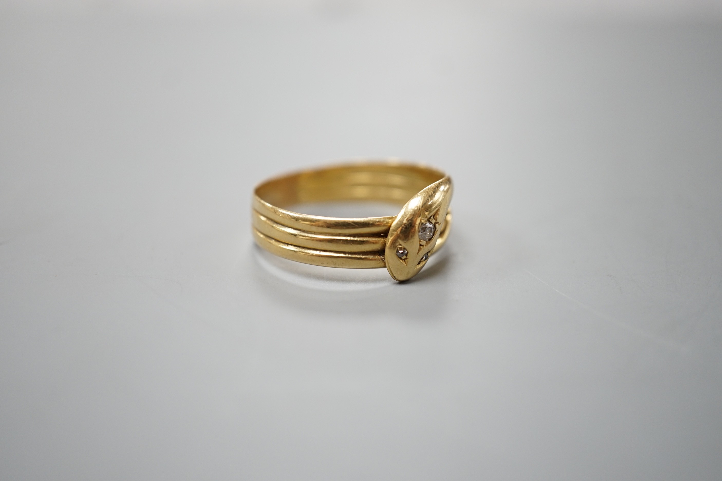 An Edwardian 18ct gold and diamond chip set serpent ring, size X/Y, gross 5.6 grams.